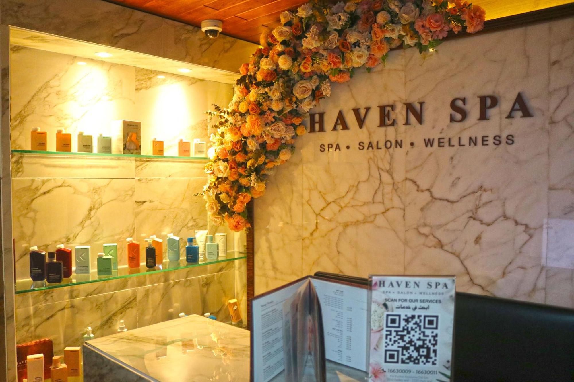 Lagoona Beach Luxury Resort And Spa Manama Eksteriør bilde The photo shows the interior of a spa called "Haven Spa." The wall is decorated with beautiful artificial flowers, creating an inviting atmosphere. There are several shelves displaying various colorful bottles and products, likely for skincare or wel