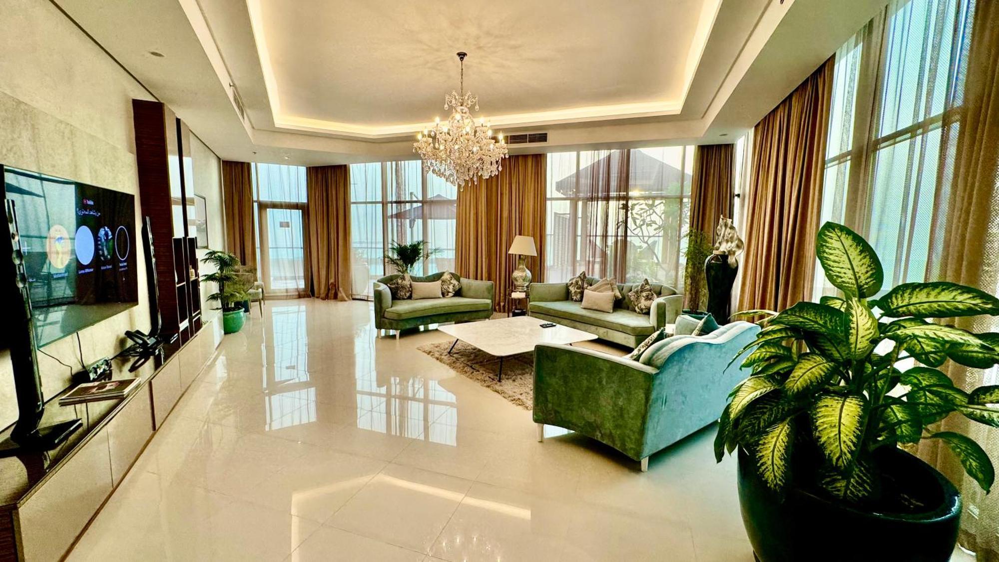 Lagoona Beach Luxury Resort And Spa Manama Eksteriør bilde The photo depicts a spacious and elegantly designed living room. The room features large windows allowing natural light to flood in, accompanied by sumptuous curtains. The furniture includes a pair of soft green sofas and a centerpiece coffee table s