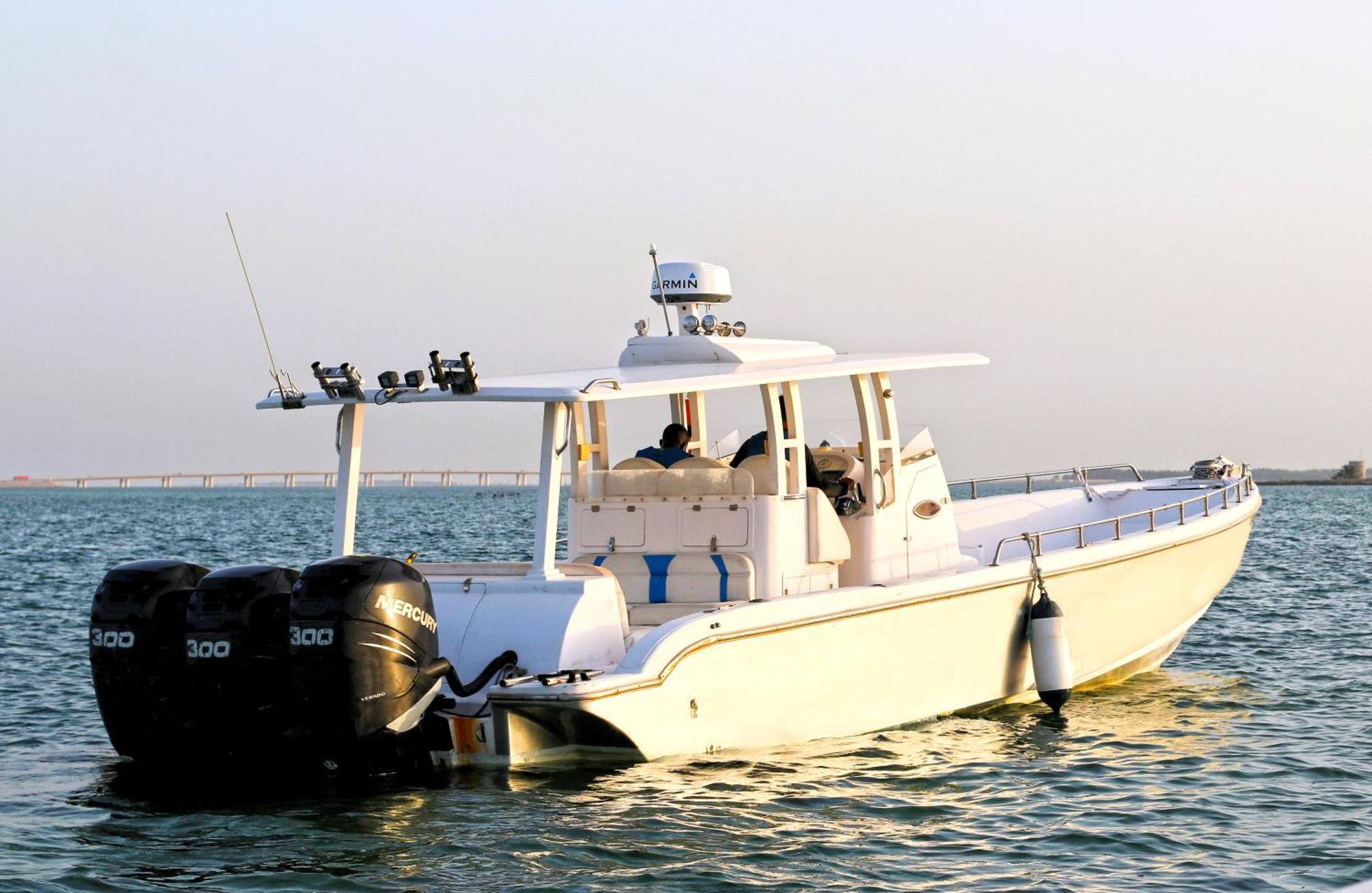Lagoona Beach Luxury Resort And Spa Manama Eksteriør bilde The photo shows a large, white motorboat equipped with three powerful outboard engines at the stern. The boat has a sleek design, with a spacious open deck and a covered cabin area that likely provides shelter and controls for navigation. The scene i