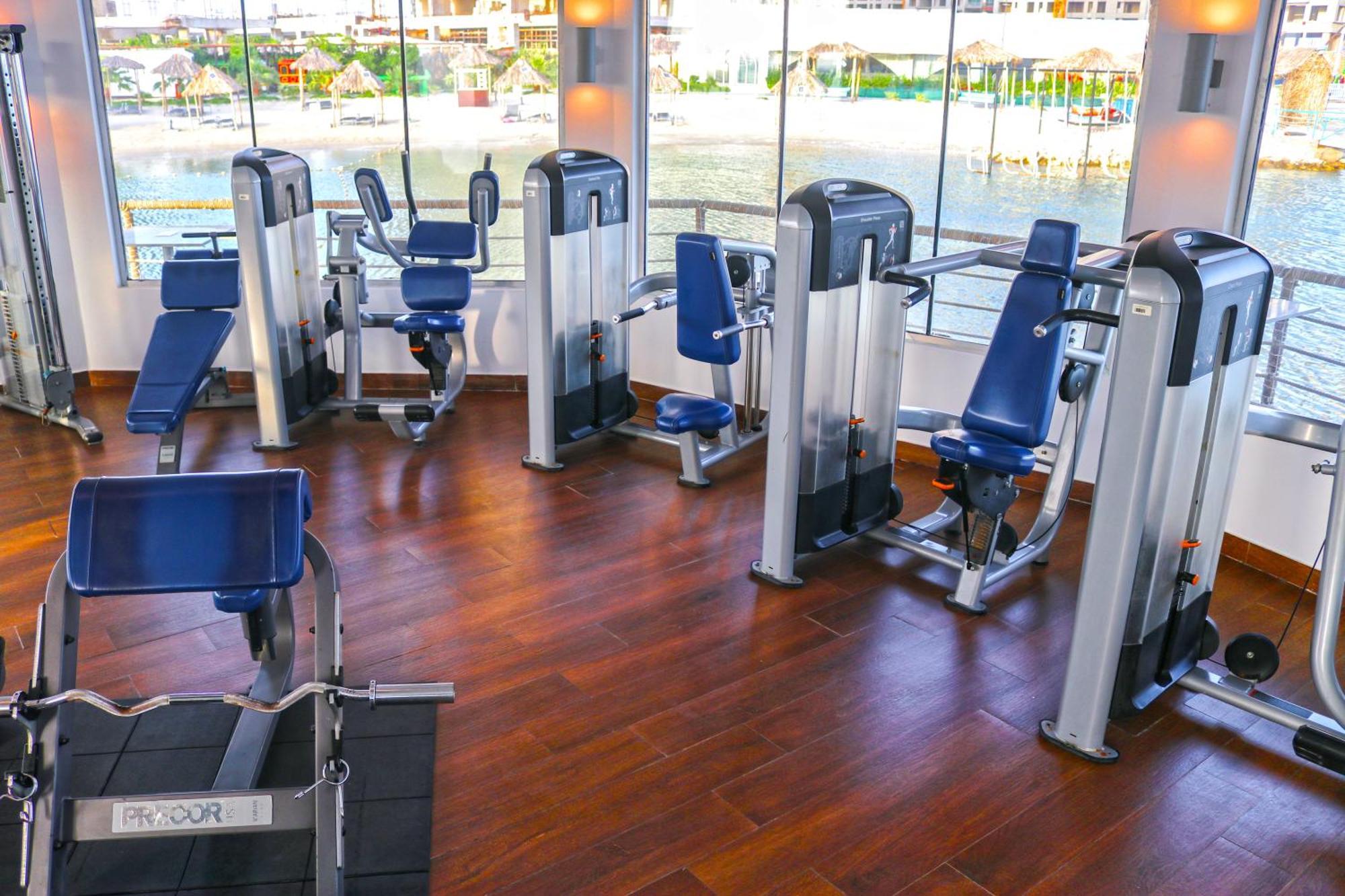 Lagoona Beach Luxury Resort And Spa Manama Eksteriør bilde The photo shows a gym or fitness center with several pieces of exercise equipment. There are multiple machines designed for strength training, including seated machines with padded seats and backrests. The equipment appears to have a modern design an
