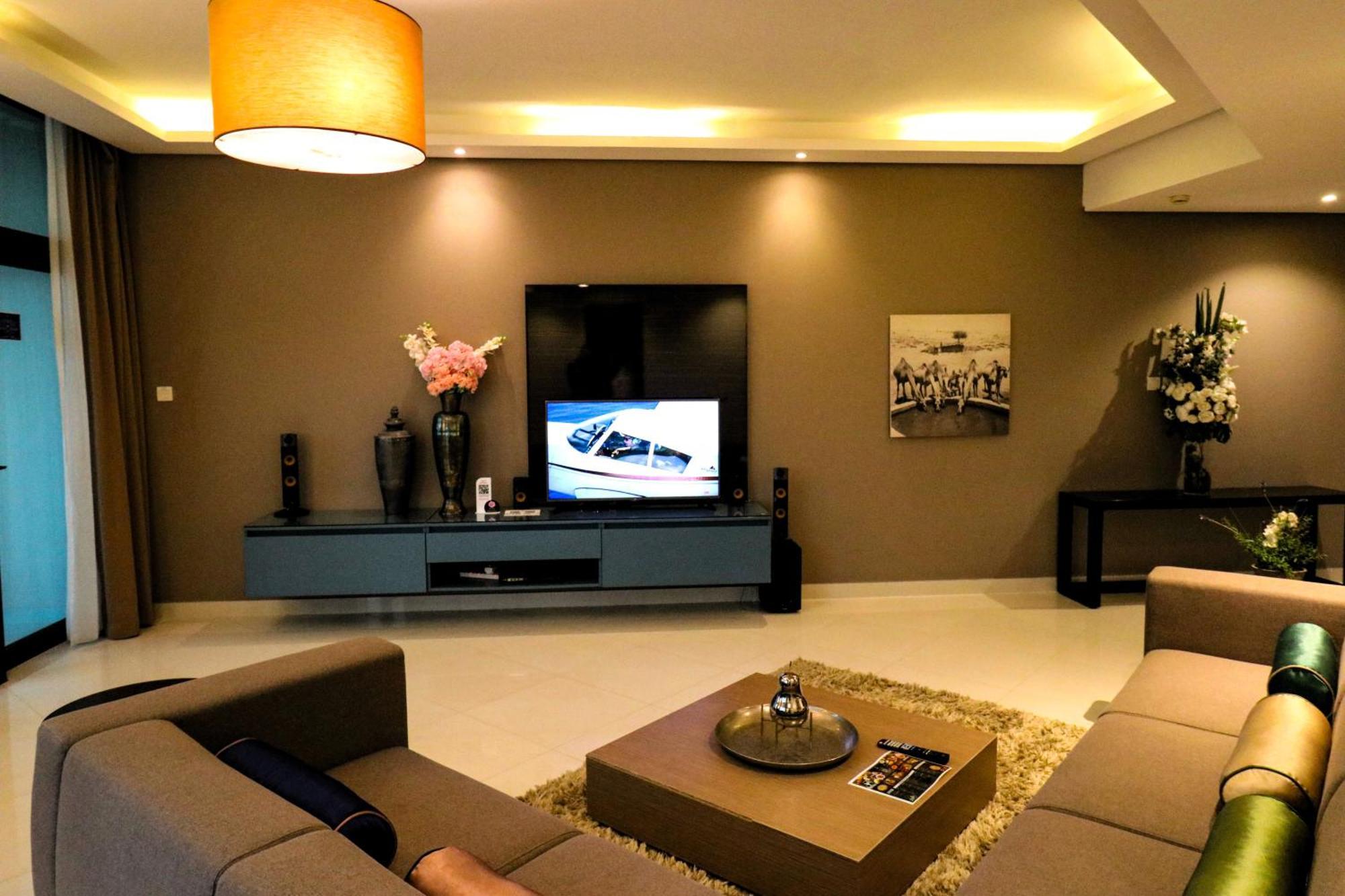 Lagoona Beach Luxury Resort And Spa Manama Eksteriør bilde The photo shows a modern living room with a neutral color palette. Key features include:

- A comfortable seating area with a sofa arranged around a coffee table.
- A minimalist coffee table with a decorative item on top.
- A large flat-screen televi